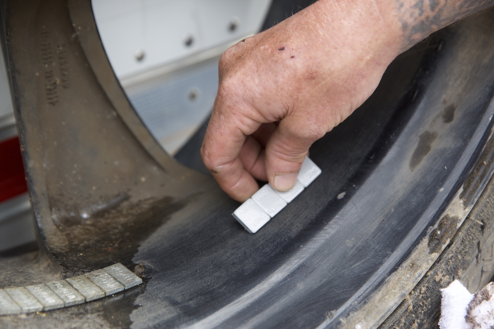 Pressing an adhesive wheel weight onto the prepared bond area